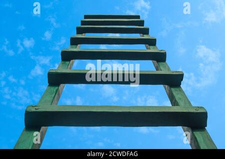 Greifen nach Green Ladder, die zu EINEM blauen Himmel führt Stockfoto