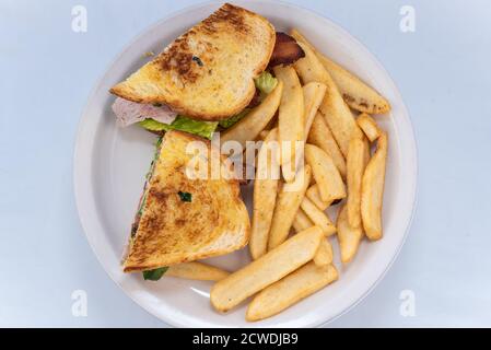 Blick von oben auf eine großzügige Mahlzeit mit einem herzhaften geschichteten Fleisch, Avocado, Speck, Sandwich hoch auf dem Teller gestapelt. Stockfoto