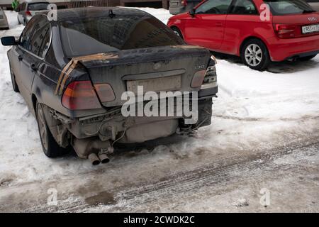 Dreckig und beschädigt Business-Klasse Auto Limousine geparkt auf Winterstraße, Back bamper fehlt, Kofferraum ist mit Klebeband befestigt, aber Fenster sind getönt und Stockfoto