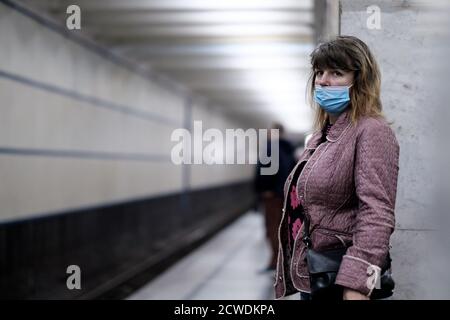 Moskau. Russland. 28. September 2020 EINE junge Frau, die eine medizinische Schutzmaske trägt, steht auf dem Bahnsteig einer U-Bahn-Station und wartet darauf, an Bord der zu gehen Stockfoto