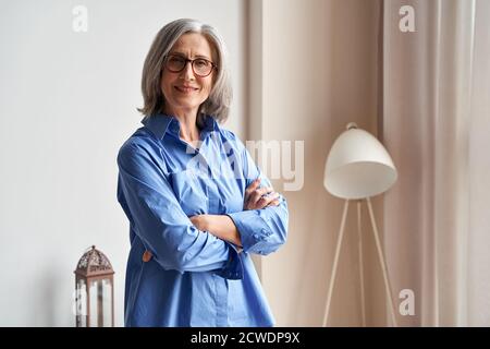 Lächelnd selbstbewusst ältere Dame stehende Arme gekreuzt Blick auf Kamera, Porträt. Stockfoto