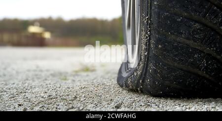 Nahaufnahme des flachen Hinterreifens am Fahrzeug. Das rechte hintere zerbrochene Weel. Beschädigte Hinterräder auf dem Parkplatz. Stockfoto