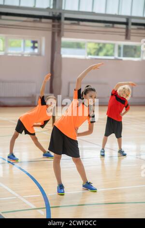 Drei Kinder trainieren im Fitnessstudio und biegen sich an die Links Stockfoto