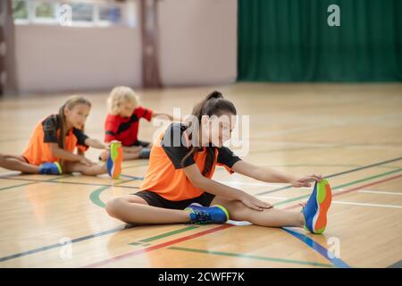 Drei Kinder in heller Sportbekleidung mit PE-Unterricht Stockfoto