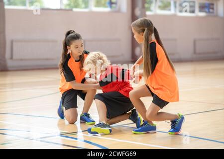 Zwei Mädchen helfen ihrem Freund in der Turnhalle Stockfoto
