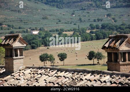 Panoramablick auf die Landschaft Umbriens vom Dorf Spello Und zwei Kamine auf dem Hausdach im Vordergrund Ein sonniger Sommertag Stockfoto