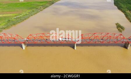 Brücke über den Cagayan River, Philippinen, Luftaufnahme. Straßenbrücke über einen breiten Fluss. Autos fahren auf der Brücke. Landschaft, landwirtschaftliche Felder in der Nähe des Flusses. Stockfoto