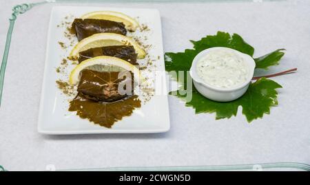 Teller Dolma mit Zitrone. Dolma - gefüllte Traubenblätter mit Reis und Gemüse Stockfoto