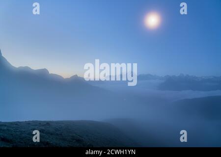 Vollmond im nebligen Himmel über Marmolada in der Abenddämmerung, Dolomiten, Trentino, Italien Stockfoto