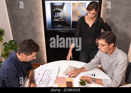 Drei junge Architekten diskutieren gemeinsam in einem Konferenzraum das neue Interior Design Konzept für eine Markenpräsentation. Junge Unternehmer arbeiten Stockfoto