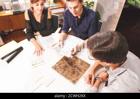 Drei junge Architekten diskutieren gemeinsam in einem Konferenzraum das neue Interior Design Konzept für eine Markenpräsentation. Junge Unternehmer arbeiten Stockfoto