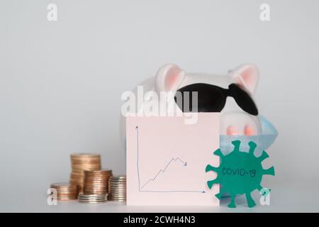 Der Zusammenbruch der Finanzmärkte und die Gefahr für finanzielle Ersparnisse aufgrund eines Pandemie-Virus.Masked Sparschwein Stockfoto