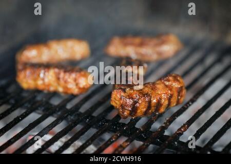 Geringe Schärfentiefe (selektiver Fokus) mit rumänischer traditioneller Mici (mititei), gegrillte Hackfleischrollen in zylindrischer Form auf dem Grill Stockfoto