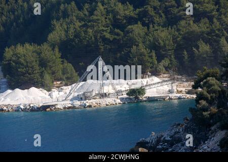 Thasos, Griechenland, 02. Oktober 2019: Weiße Marmormine am Ufer des Meeres mit Förderband am Strand von Porto Vathy auf der Insel Thasos. Stockfoto