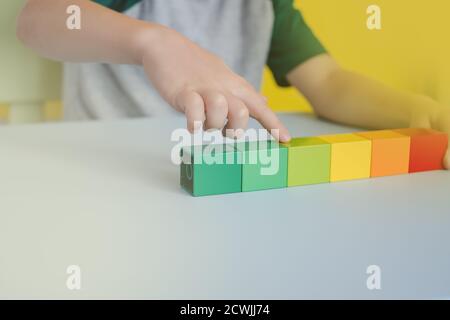 Nahaufnahme von Kinderhänden, die farbige Blöcke in Linien zählen Auf dem Tisch Stockfoto