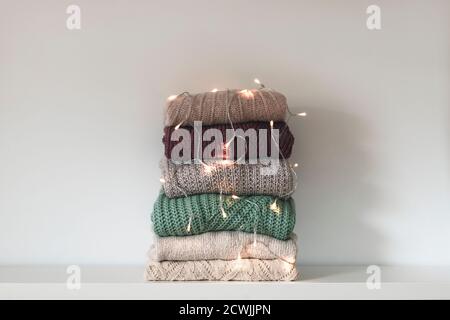 Warmer Strickpullover für Damen auf weißem Hintergrund. Girlande Lichter als Dekoration. Winterurlaub Konzept. Stockfoto