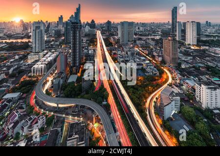 Sonnenaufgang über der Trident Straße bei Sathorn, Taksin Brücke und beleuchteter Verkehr in Bangkok, Thailand Stockfoto