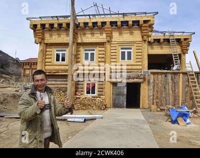 Chengdu, Chinas Provinz Sichuan. März 2017. Ein einst armutsgeplagter Dorfbewohner posiert für ein Foto mit seinem neuen Haus im Bau im Dorf Geka der Stadt Mazi, Bezirk Dawu der tibetischen Autonomen Präfektur Garze, südwestlich der chinesischen Provinz Sichuan, 11. März 2017. Quelle: Liu Kun/Xinhua/Alamy Live News Stockfoto