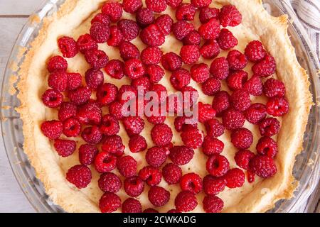 Zubereitung von Shortbread Pie mit Himbeeren auf einem weißen Holzhintergrund, Draufsicht close up. Stockfoto