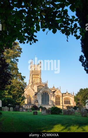 Die Kirche des heiligen Johannes des Täufers aus dem Garten der Erinnerung bei Sonnenaufgang im Herbst. Cirencester, Cotswolds, Gloucestershire, England Stockfoto