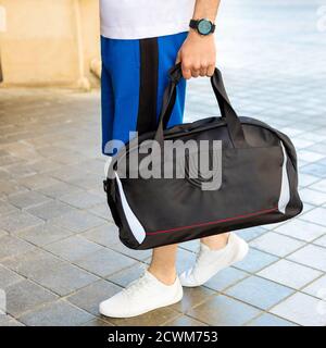 Junger Mann, der eine schwarze Sporttasche in der Nähe hält Stockfoto