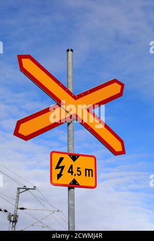 Unbeaufsichtigte Bahnüberfahrt Schild informiert über die Höhe der obenliegenden elektrischen Kabel durch eine kleine Landstraße in Finnland. Stockfoto