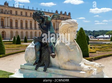 Weiße Sphinx-Statue und Amor-Bronzestatue im Versailles Gärten Stockfoto