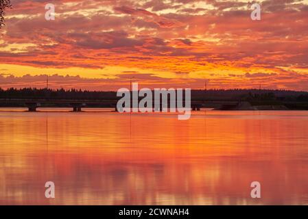 Der helle Sonnenuntergang spiegelt sich im glatten Wasser des Sees wider. Stockfoto