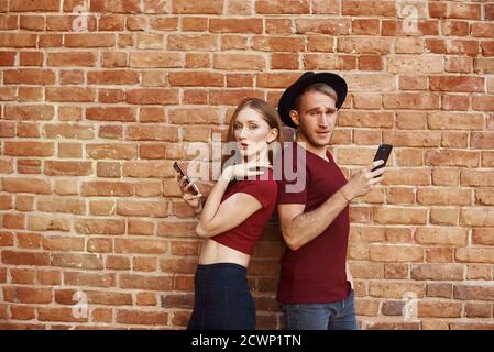 Das Paar benutzt das Telefon. Frau und Mann stehen mit dem Rücken zueinander am Telefon. Stockfoto