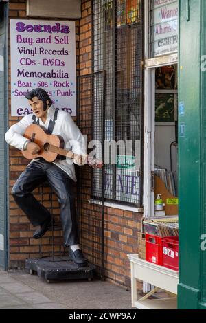 Eine Statue von Elvis Presley, der eine Gitarre vor einem spielt Plattenladen Stockfoto