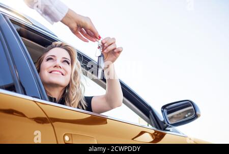 Schöne Frau bekommt den Schlüssel aus dem Auto Stockfoto