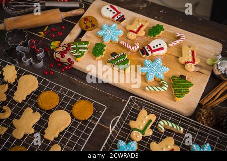 Frisch gebackene Weihnachtsplätzchen auf Holztisch. Blick von oben auf Weihnachtsbaum und Schneemann Kekse. Stockfoto