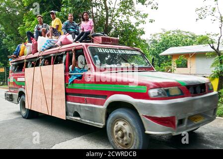 Ein alter farbenfroher jeepney-LKW im philippinischen Stil mit jungen Leuten, die zusammen mit Reissäcken auf dem Dach sitzen, Antique, Visayas, Philippinen, Asien Stockfoto