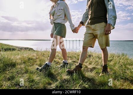 Unbekanntes Paar Wanderer, die Hände halten und auf Gras laufen Zusammen reisen Stockfoto