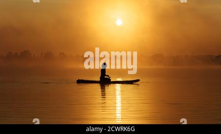 Mann sitzt auf dem Brett und genießt den wunderschönen Sonnenaufgang Stockfoto