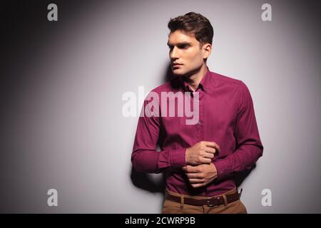 Gut aussehender junger Mann, der sich an einer Wand lehnte, während er seine Hülse festhielt. Stockfoto