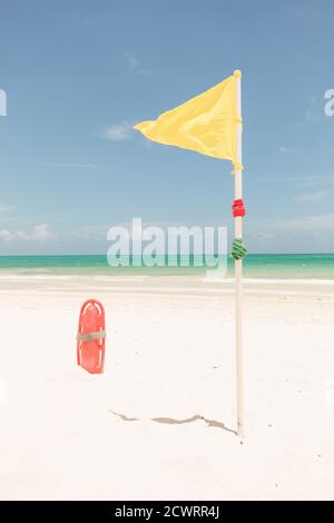 Gelbe Flagge und rote Plastic Rettungsschwimmer Rohr am Strand. Stockfoto