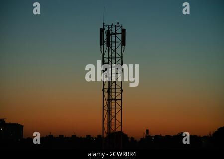 Silhouette des Antennenkommunikationsturms des Mobilfunkanbieters gegen den Hintergrund des Abends orange-blauer Himmel Stockfoto