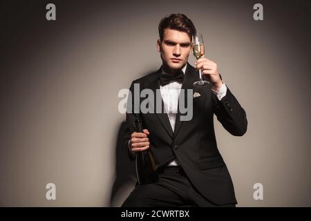 Eleganter Geschäftsmann, der eine Flasche und ein Glas Champagner in der Hand hält. Stockfoto