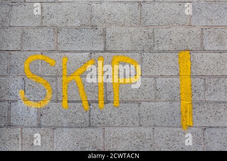 Das Wort SKIP graffisted auf einer Betonblockwand Stockfoto