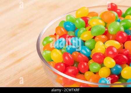 Nahaufnahme eines leckeren Jelly Beans Süßigkeiten in einem Glasschale isoliert auf einem hölzernen Hintergrund Stockfoto