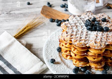 Frisch gebackene hausgemachte Waffeln herzförmig mit Heidelbeeren auf einem gestapelt Platte Stockfoto