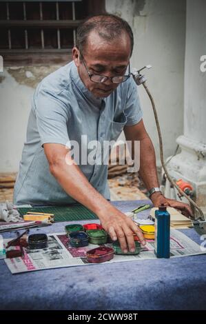 Alter asiatischer Mann, der ein Kunstwerk auf der Straße schuf Stockfoto