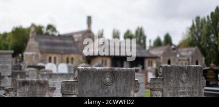 Gebetshalle außerhalb des Fokus in der Ferne. Grabsteine im Fokus im Vordergrund auf dem historischen Jüdischen Friedhof Willesden, Nordwesten Londons, Großbritannien Stockfoto