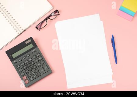 Büroflachlage. Leere weiße Blatt Papier mit Stift sind auf rosa Schreibtisch Tisch mit Rechner und Suplpies. Draufsicht mit Kopierbereich. Äh Stockfoto