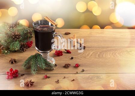 Tasse weihnachtlicher Glühwein oder Gluhwein mit Gewürzen und auf rustikalem Holztisch. Traditionelles Getränk im Winterurlaub. Weihnachtliche Glühwein und Gewürze Stockfoto