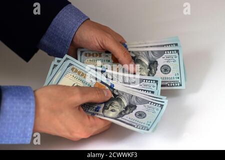 Die Hände des Geschäftsmanns arbeiten für das Geld. Der Geschäftsmann im Anzug zählt die Dollars. Stockfoto