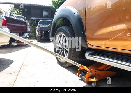 Das Fahrzeug mit hydraulischem Wagenheber zur Reparatur anheben. Zum Reifenwechsel Räder entfernen. Stockfoto