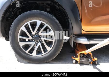 Das Fahrzeug mit hydraulischem Wagenheber zur Reparatur anheben. Zum Reifenwechsel Räder entfernen. Stockfoto