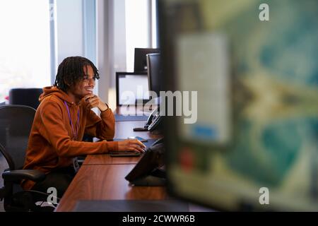 Lächelnder junger Geschäftsmann, der im Büro am Computer arbeitet Stockfoto